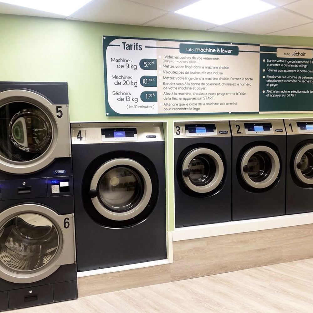 Interieur de la laverie N'Clean : machines a laver et secheurs Primus, tarifs et mode d'emploi affiches